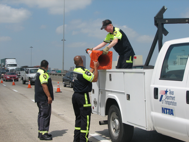 3 people setting up cones on a highway