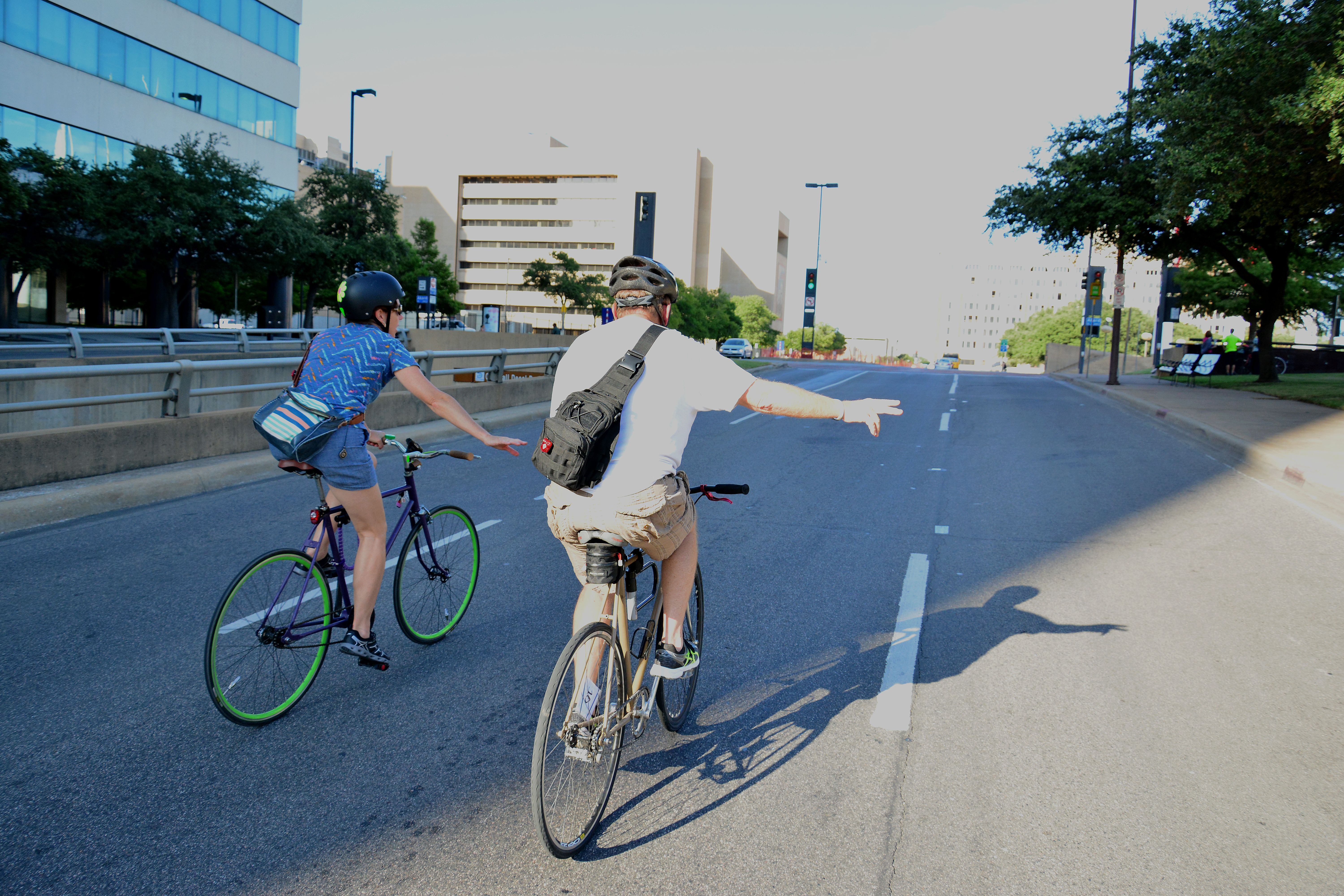Two bicyclers signaling to change lanes