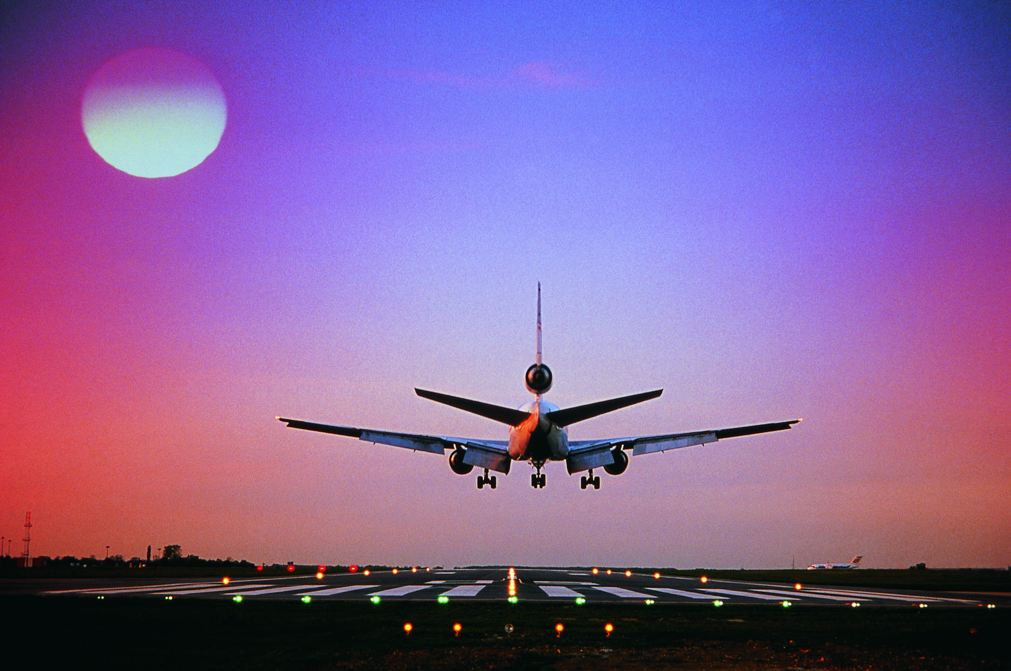 Airplane approaching runway with moon in view