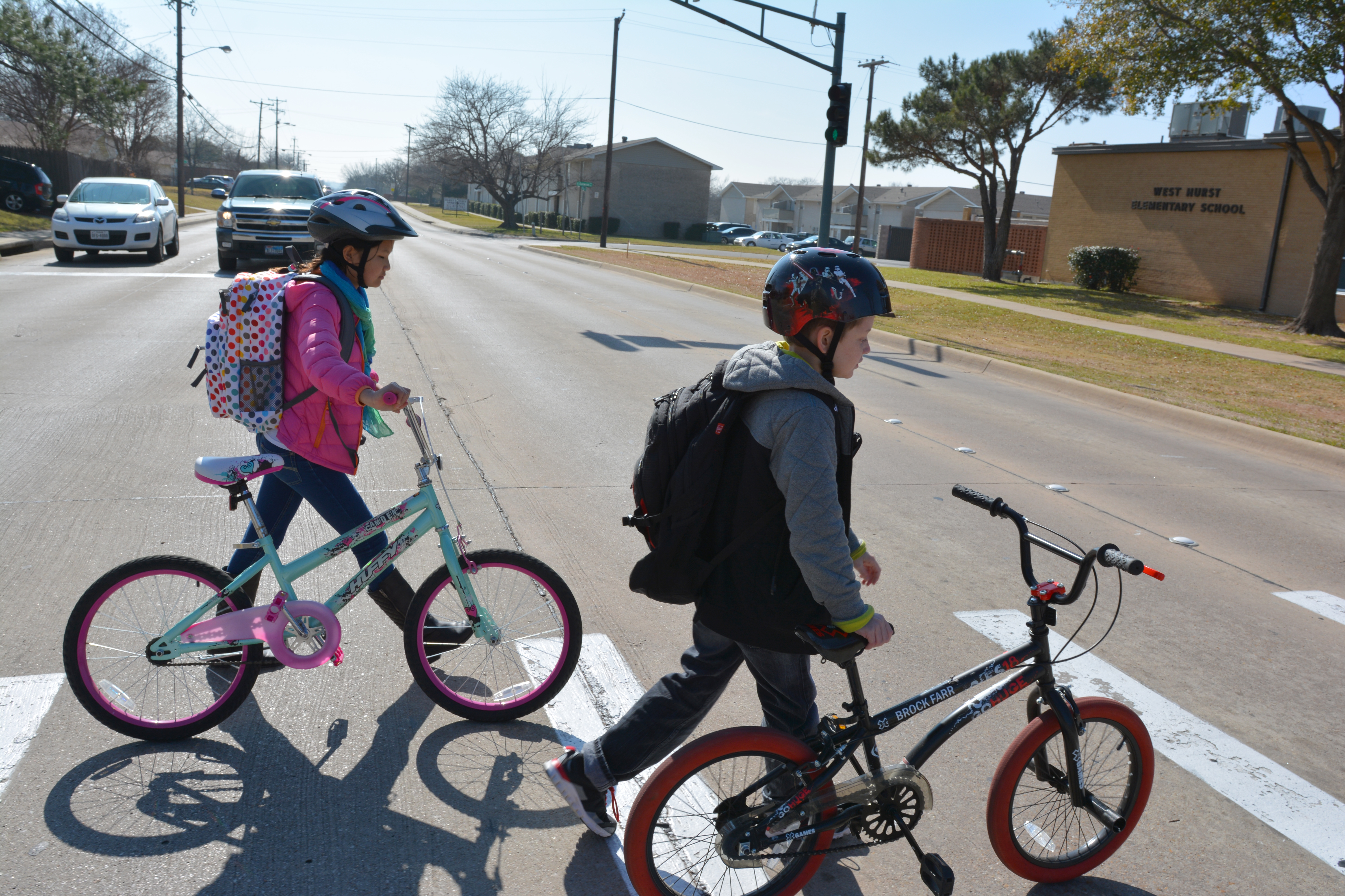 Young boy and girl walking bikes in crossing
